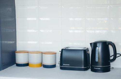 a toaster and three cups on a kitchen counter at Deluxe Guest Suite at Warner Beach in Kingsburgh