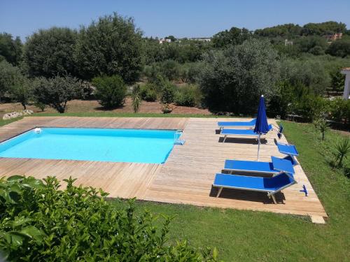 een zwembad met blauwe ligstoelen en een parasol bij Holiday Home Trullo Antico in Ostuni