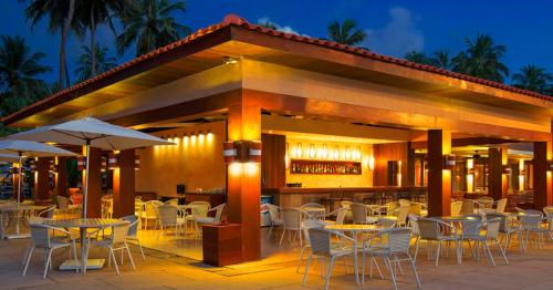 a restaurant with tables and chairs and a bar at JATIÚCA SUITES RESORT - FLAT VISTA MAR in Maceió