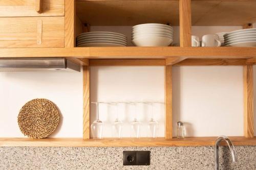 - une armoire de cuisine avec des assiettes et de la vaisselle dans l'établissement Ferreiros - Wood Design apartments, à Pontedeume