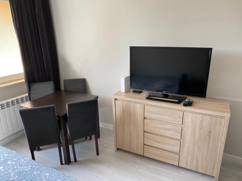 a room with a television and a table with chairs at Apartament na Broniewskiego in Gdańsk
