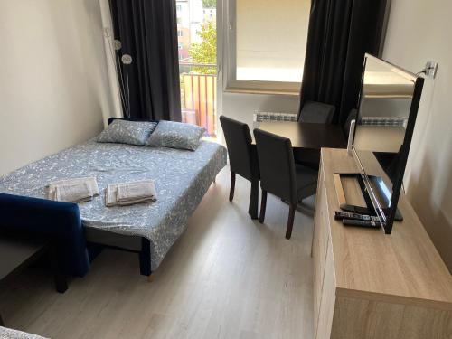 a room with a bed and a table and a desk at Apartament na Broniewskiego in Gdańsk
