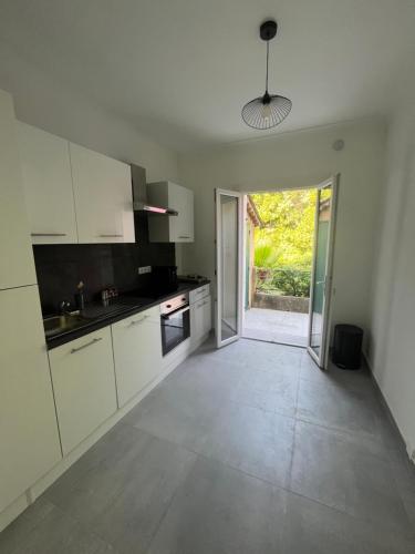 an empty kitchen with white cabinets and a sliding glass door at Villa 2 chambres rénovée Juillet 2023 - vue mer - parking privé in Grasse