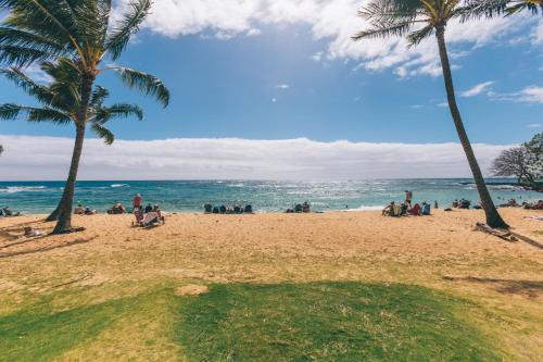 a group of people on a beach with palm trees at Updated 1Br 1Ba Condo in the Kiahuna Plantation Resort near Poipu Beach 430 in Koloa