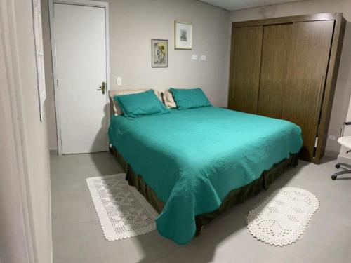 a bedroom with a green bed with a wooden cabinet at Dith's House in Campos do Jordão