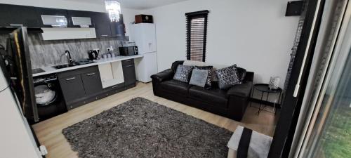 a living room with a black couch and a kitchen at The Cwtch in Cardiff