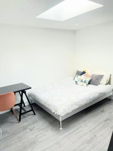 a bed sitting in a room next to a table at Modern 2 Bedroom Flat With Garden LONDON in Northolt