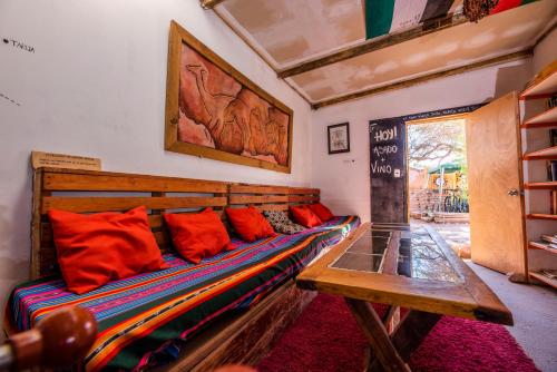a room with a couch with red pillows and a table at Casa Voyage Hostel in San Pedro de Atacama