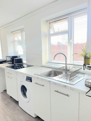 a white kitchen with a washing machine and a sink at Modern 2 Bedroom Flat With Garden LONDON in Northolt