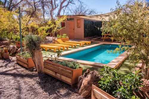 a pool with tables and benches in a backyard at Casa Voyage Hostel in San Pedro de Atacama