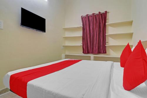 a bedroom with a bed with red pillows and a tv at 80983G RBS Square Langer Houz in Haidar Sāhibgūda
