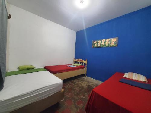 1 dormitorio con 2 camas y pared azul en Casa Esmeralda, en Moyogalpa