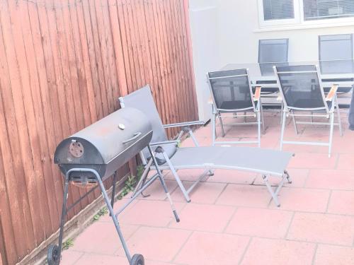 a barbecue grill and chairs on a patio at Modern 2 Bedroom Flat With Garden LONDON in Northolt