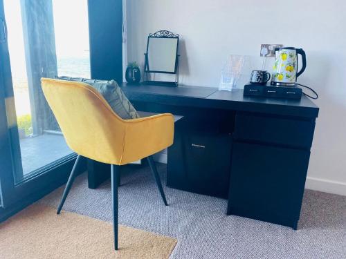 a desk with a yellow chair in a room at Luxury beach front rooms- PMA in Kirkcaldy