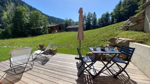 a table and chairs on a wooden deck with an umbrella at Chalet Birdie in Le Grand-Bornand