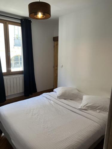 uma cama branca num quarto com uma janela em Appartement en bord de Seine em Rouen
