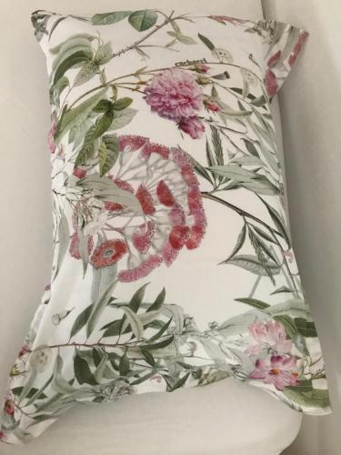 un oreiller avec un motif floral assis sur une chaise dans l'établissement Le MAS du Paradis Bleu, à Saint-André-de-Cruzières