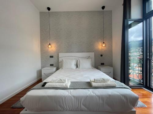 a bedroom with a white bed and a large window at Sea and Sun 4 You - Villa Oliveira in Funchal