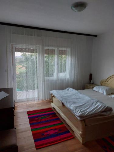 a bedroom with a bed and a rug and windows at Guest House Planinic in Čitluk