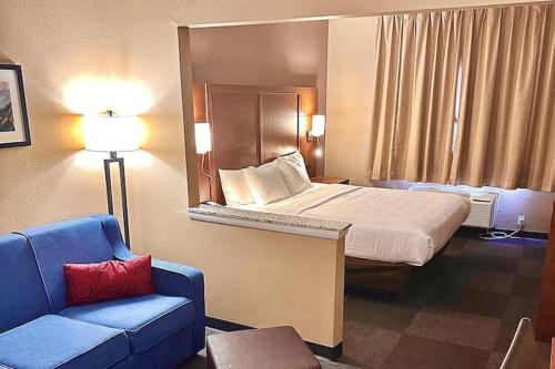 a hotel room with a bed and a blue couch at Baymont by Wyndham Phoenix North in Phoenix