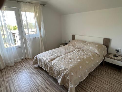 a bedroom with a bed with a comforter and two windows at Apartmani Pristav in Kršan