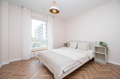 a white bedroom with a large bed and a window at Apartments 7vakarai with free parking in Vilnius