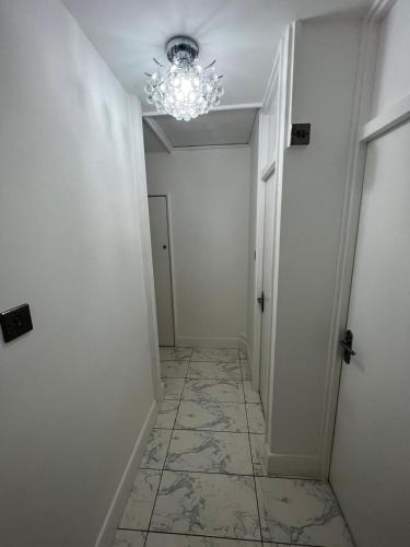 a hallway with a chandelier and a tile floor at T Lodge in Abbey Wood