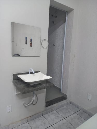 a white bathroom with a sink and a mirror at FLAT 2 - CENTRO DE ITAPIRA in Itapira