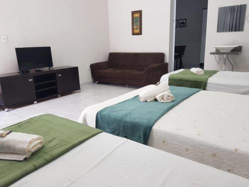 um quarto de hotel com duas camas e um sofá em FLAT 2 - CENTRO DE ITAPIRA em Itapira