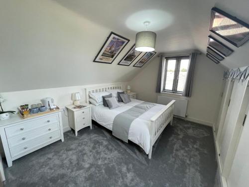 a bedroom with a white bed and a white dresser at The Top Floor in Stretham