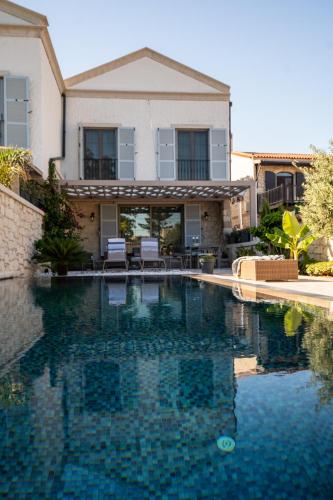 a house with a swimming pool in front of a house at Zena Hotel Alaçatı Adults Only in Alacati