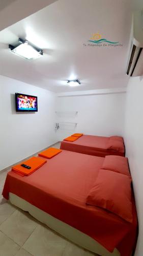 a bedroom with two beds and a tv on the wall at Posada Villa Mayo Apartamento7 familiar a 5 Min de Playa Parguito in Paraguachi