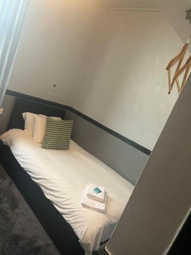 a small bed in a room with a book on it at The Charles Dickens Hotel in Wigan