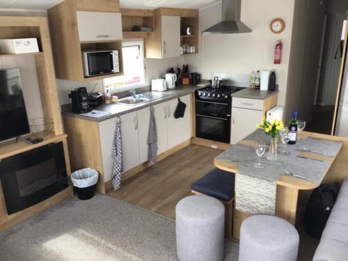 a small kitchen with a table and a counter top at Brookside West Sands Holiday Park Seal Bay Selsey in Selsey