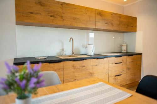 a kitchen with wooden cabinets and a wooden table at Domki Górkło in Górkło