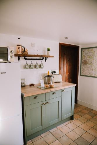 a kitchen with green cabinets and a counter top at Pebbles Cottage in Caister-on-Sea