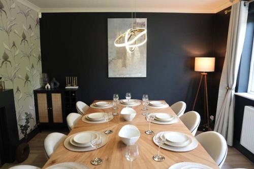 a wooden table with white plates and wine glasses at Beautiful home with hot tub near Cambridge in Royston