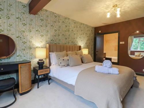 1 dormitorio con cama, escritorio y espejo en Beautiful home with hot tub near Cambridge en Royston