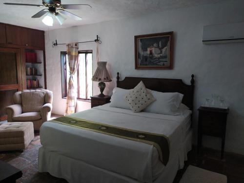 a bedroom with a large bed and a chair at Posadas Le Petit Inn in Caracas