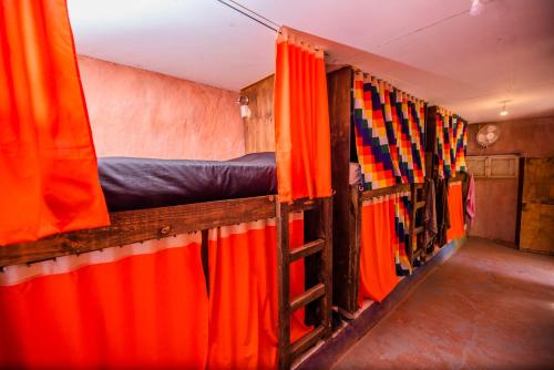 a row of beds in a room with curtains at Casa Voyage Hostel in San Pedro de Atacama