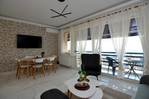 un soggiorno con tavolo, sedie e una grande finestra di La Casa Blanca a Kavala