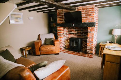 a living room with a brick fireplace and a tv at Pebbles Cottage in Caister-on-Sea