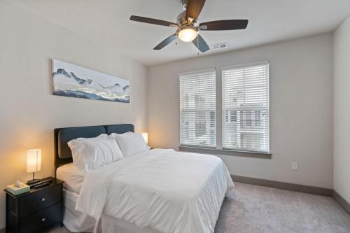 1 dormitorio con cama blanca y ventilador de techo en Comfy Retreat Balcony Views Amenities en Woodbridge
