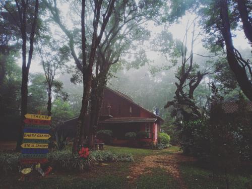 a red barn in the woods with a sign in front of it at Chalé Cores da Mata in Brumadinho