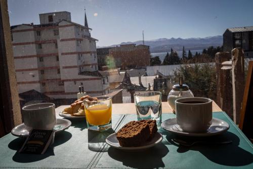a table with a breakfast of cake and orange juice at Hotel 7 Lagos in San Carlos de Bariloche