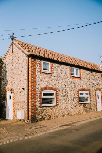 a brick building with three windows on a street at Pebbles Cottage in Caister-on-Sea