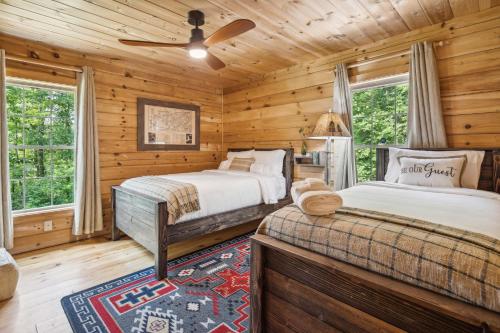 Dormitorio en cabaña de madera con 2 camas y ventilador de techo en Lake Lure Cabin Rental with Private Outdoor Oasis!, en Lake Lure