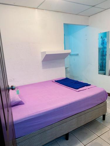 a hospital room with a bed with purple sheets at 8 Habitaciones in Managua