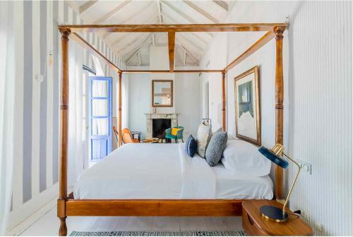 um quarto com uma cama de dossel em madeira com lençóis brancos em The Pearl - Marbella em Marbella