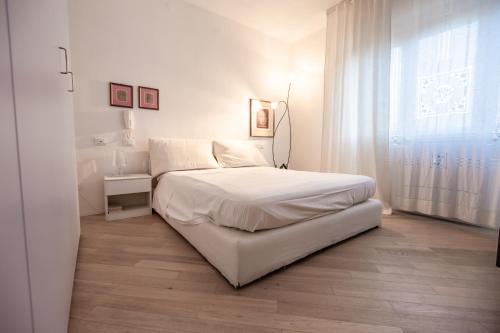 a white bedroom with a bed and a window at Casa Summer in Cecina